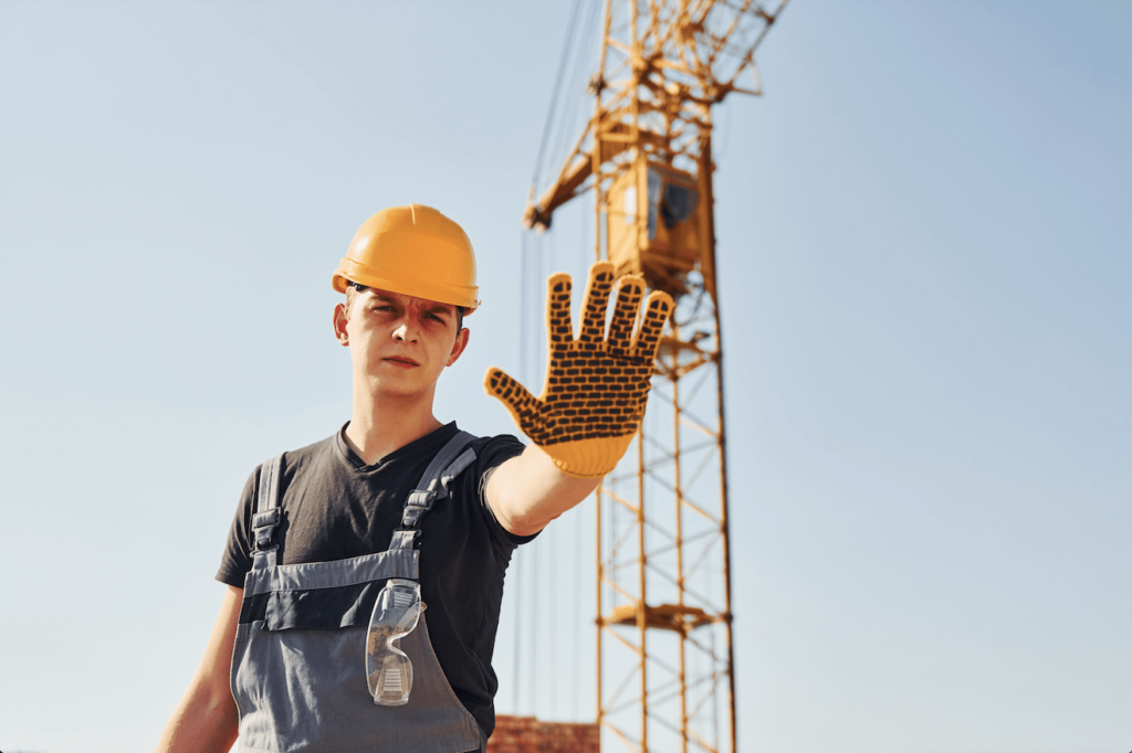 Stop Work Authority Policy: Picture of a construction worker signaling with his hand for people to stop.