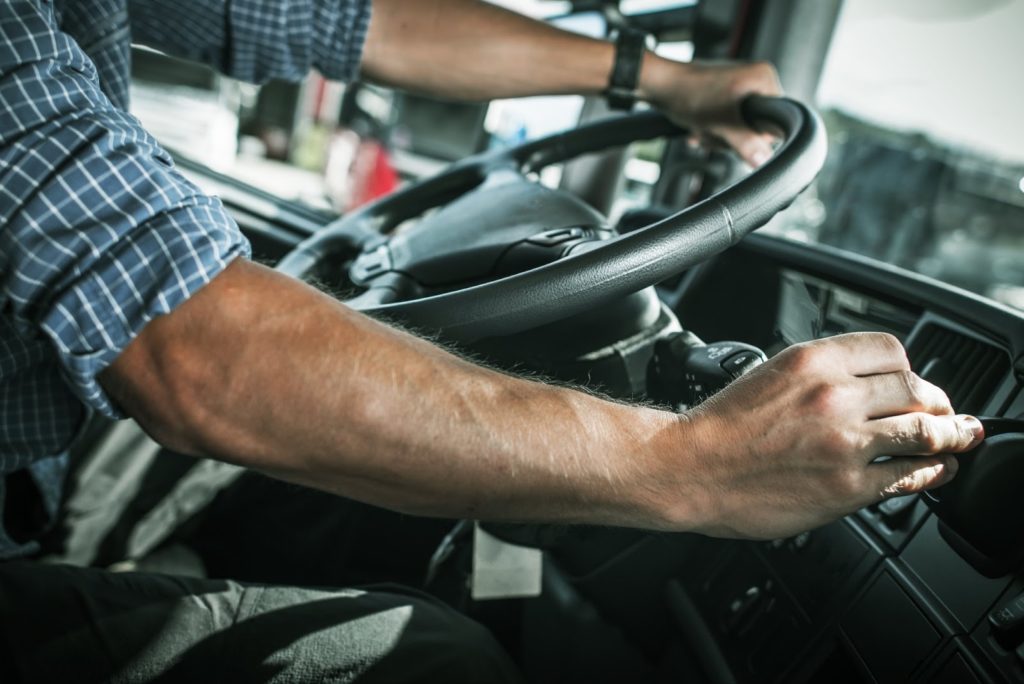 A close-up picture of hands around the steering wheel of a commercial vehicle.