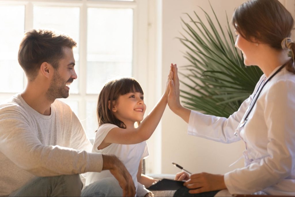 A picture of a child high-fiving her doctor after an appointment.