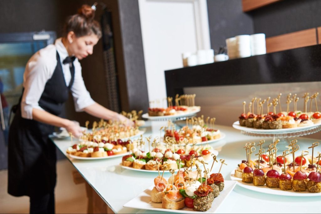 A catering employee preparing dishes at a white tie event.